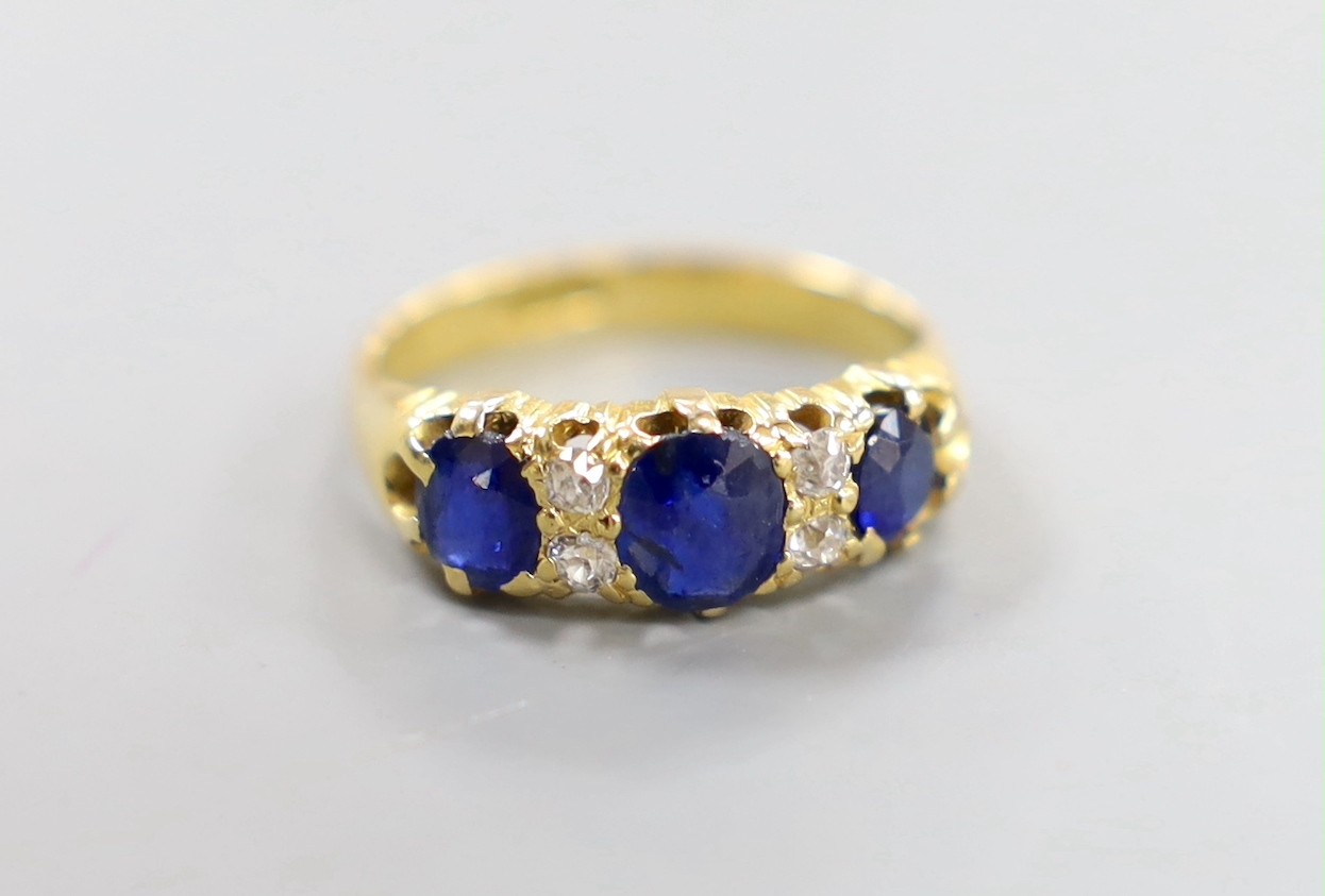 An 18ct, three stone sapphire and four stone diamond chip set half hoop ring, size L, gross weight 4 grams.